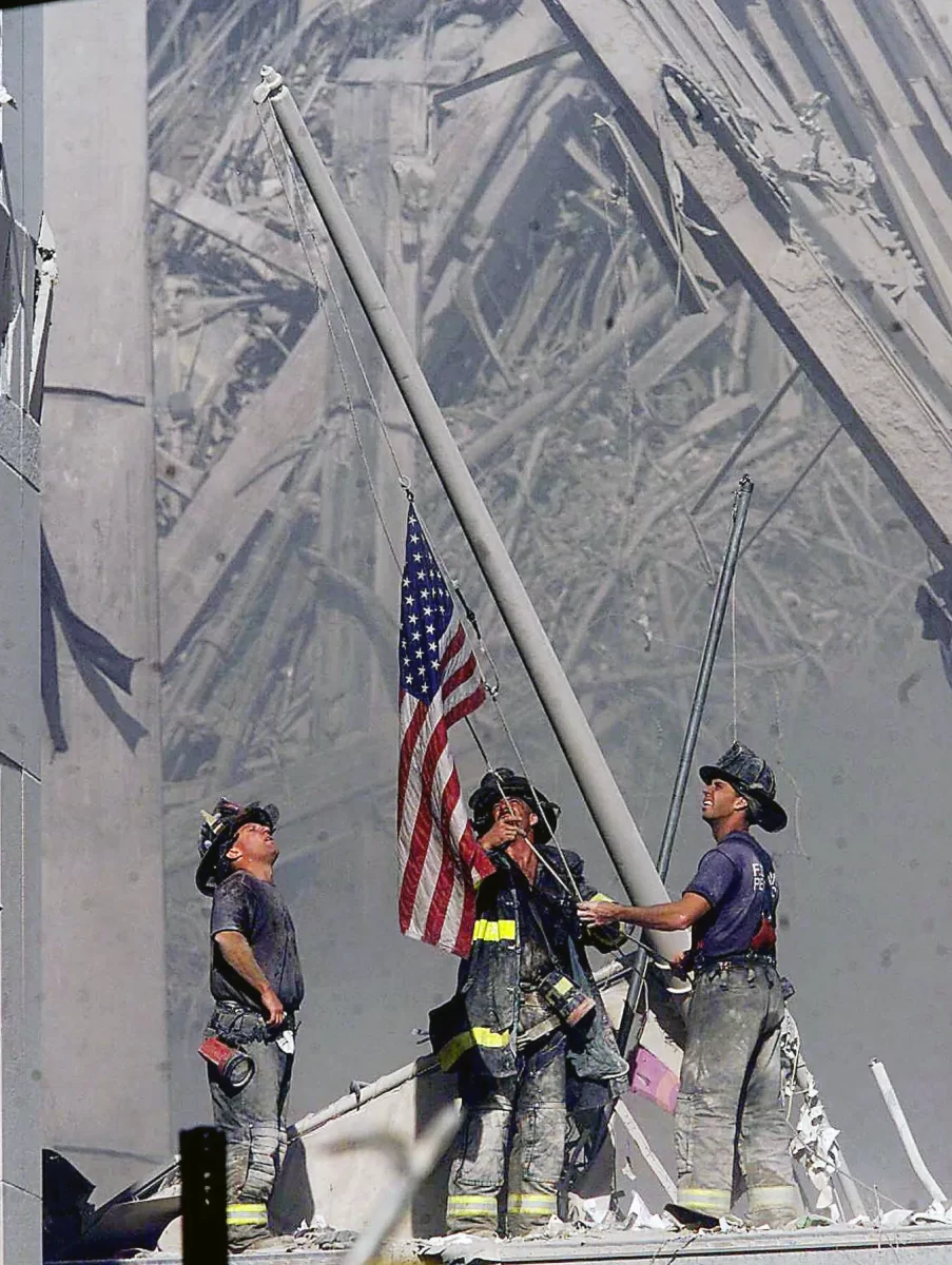 At the base of the Twin Towers, firefighters raise the flag right after the attacks