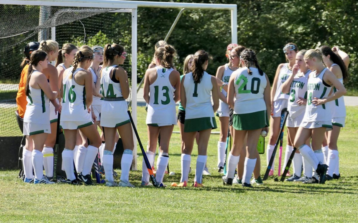 The varsity field hockey team gathers to talk during halftime .