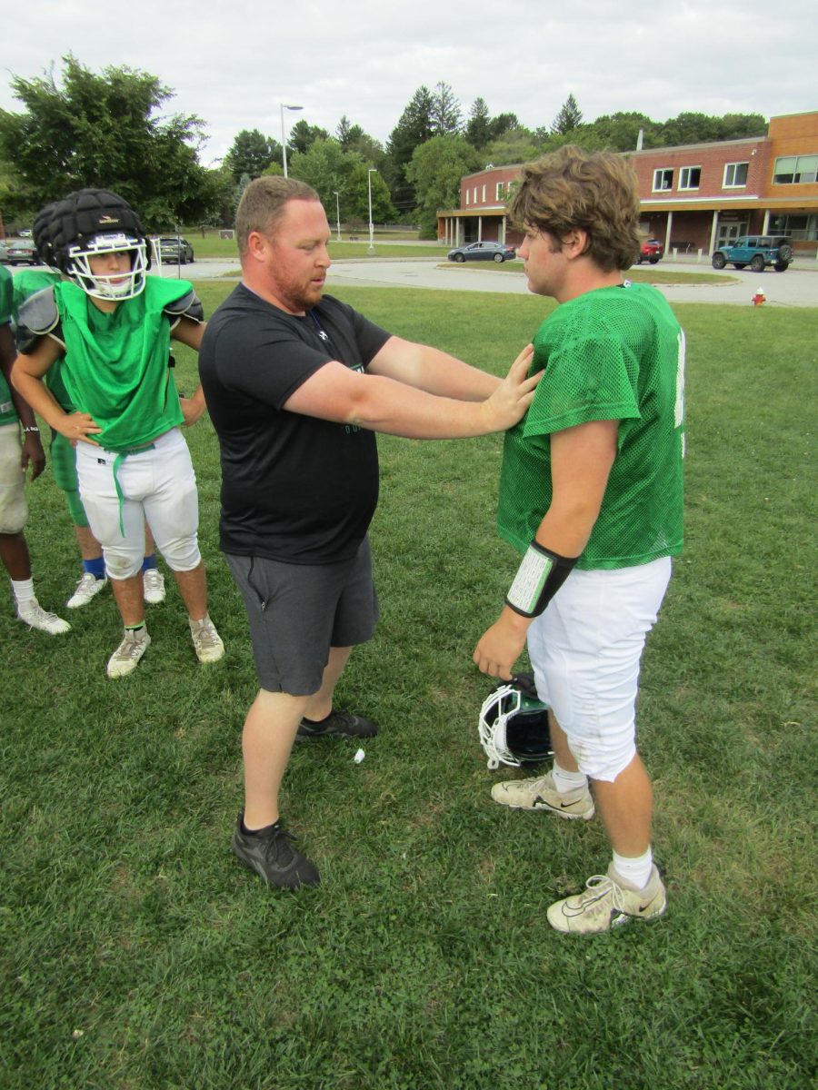 A coach gives Liam Langevin technique instruction as the football team prepares for its game Saturday. 