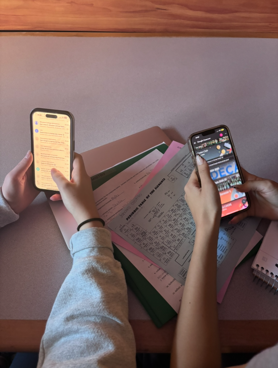 Two students using the cell phones to check their email and google classroom. 