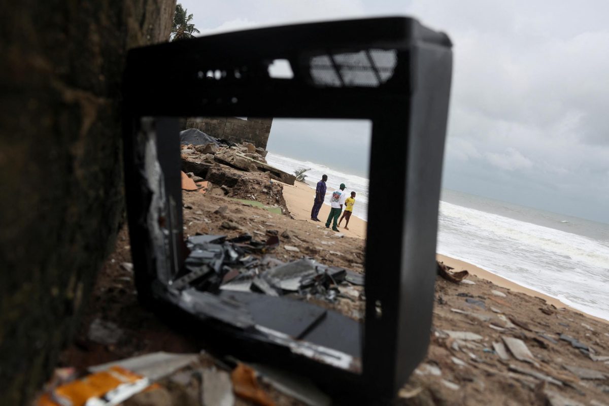 Displaced residents are seen through the frame of a broken television box on the eroded shoreline of Lepiya, one of the coastal communities affected by ocean surges, Nigeria July 8, 2025. The coastal communities have been severely affected by shoreline erosion, which locals attribute to dredging activities along the Ibeju-Lekki coastline. REUTERS/Sodiq Adelakun