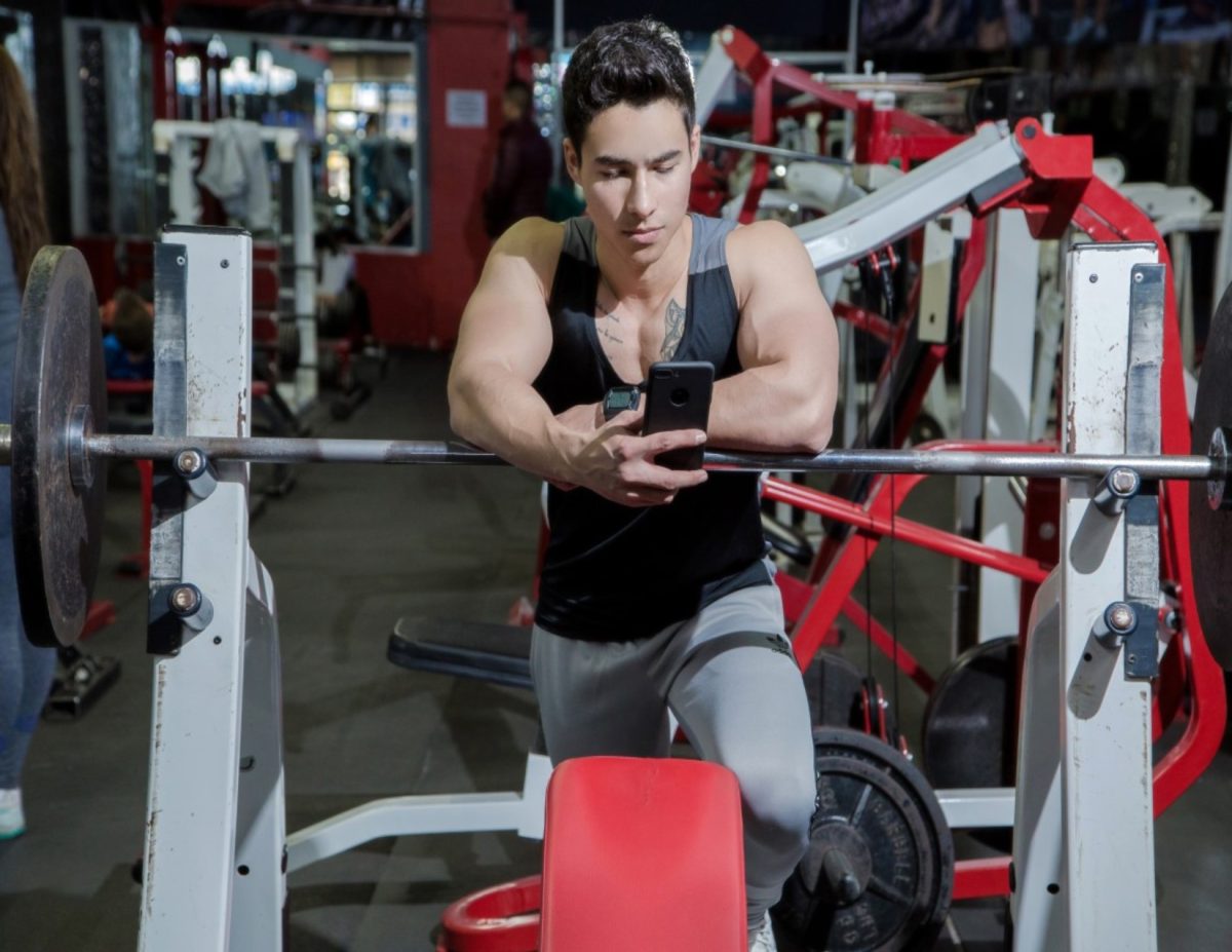 A man is distracted by his phone at the gym